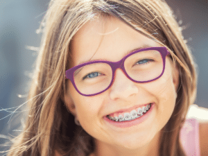 Young girl smiling with braces during early orthodontics treatment